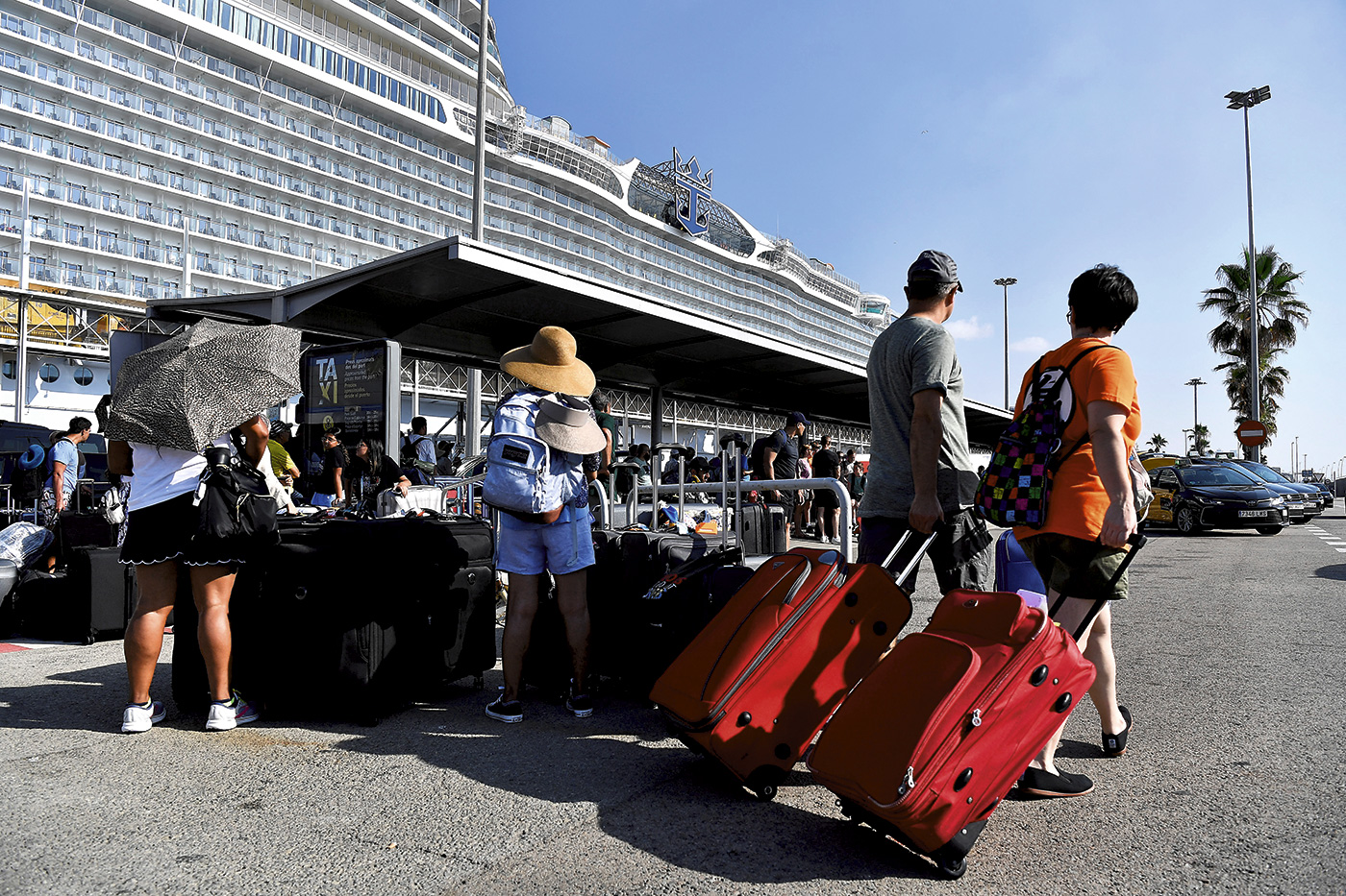 Cruceristas esperando a los taxis después de desembarcar del crucero 'Wonder of the Seas' en el puerto de Barcelona, el24 de julio de 2022.- PAU BARRENA/AFP