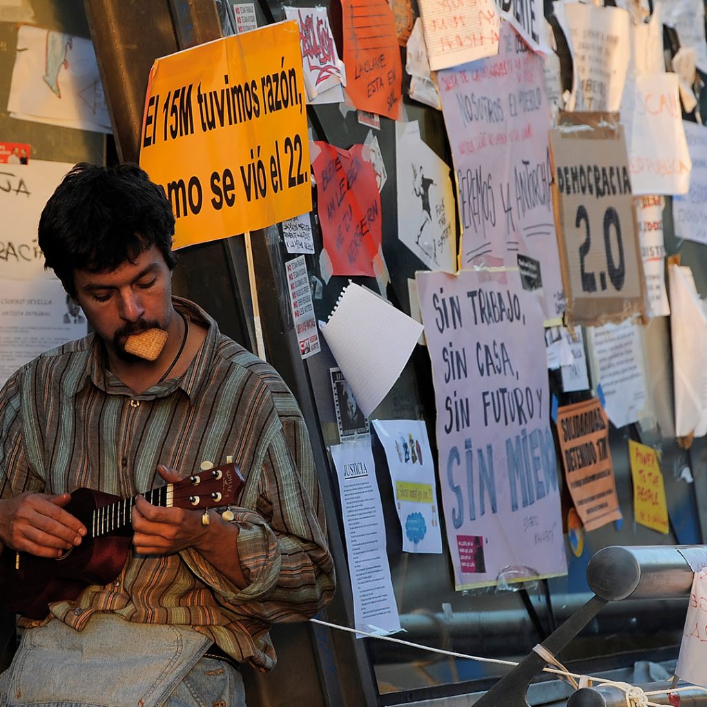 Fotografía: Un manifestante toca el ukelele en la Puerta del Sol en mayo de 2011.- DANI POZO / AFP